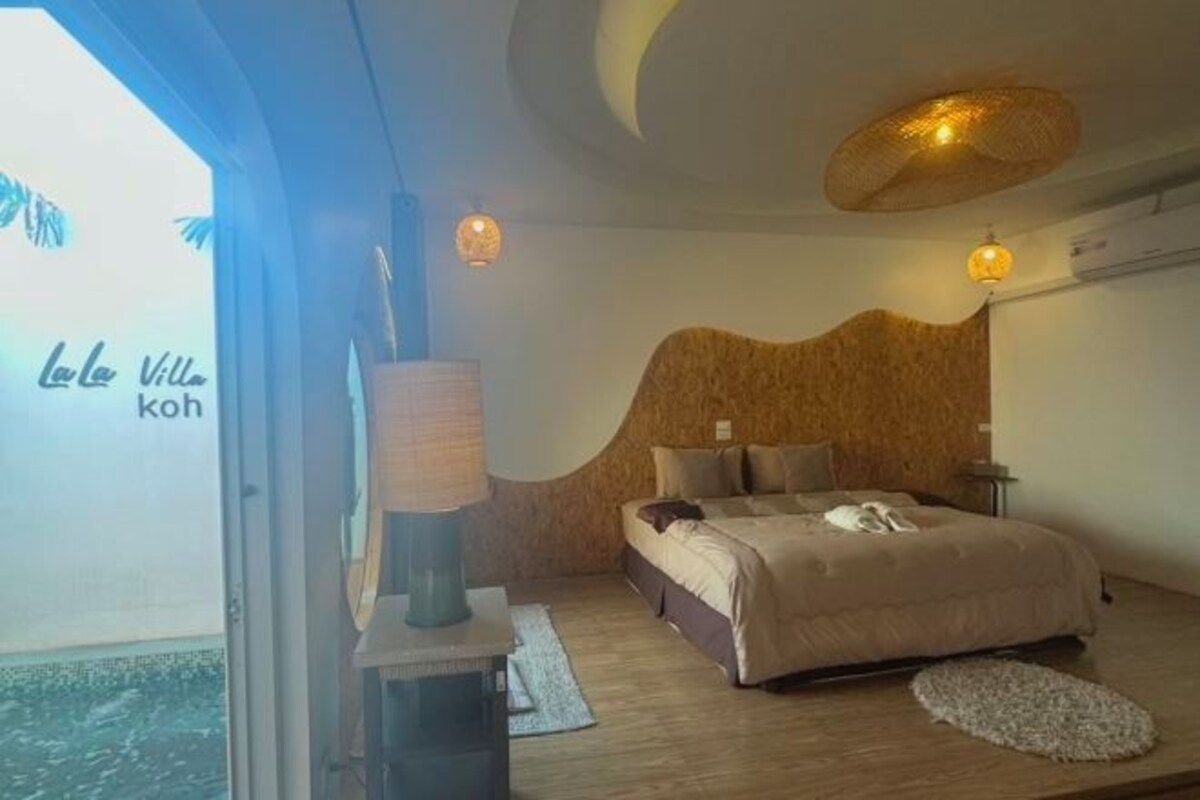 A bedroom with a bed, a lamp, and a view of the sea.