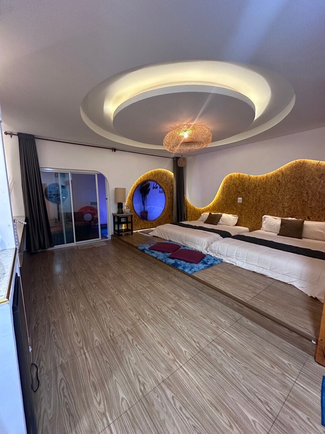Un dormitorio moderno con techo curvo, una cama grande y un elemento decorativo circular en la pared.