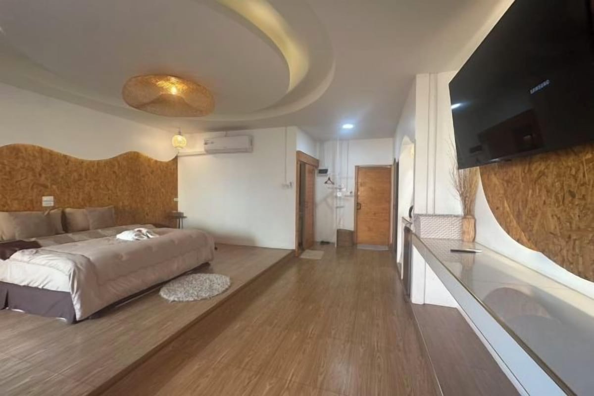 Una habitación de hotel moderna con una cama grande, un televisor de pantalla plana y una pared decorativa de madera.