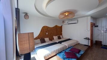 A bedroom with a wooden headboard, a bed with multiple pillows, a blue rug, and a ceiling light fixture.