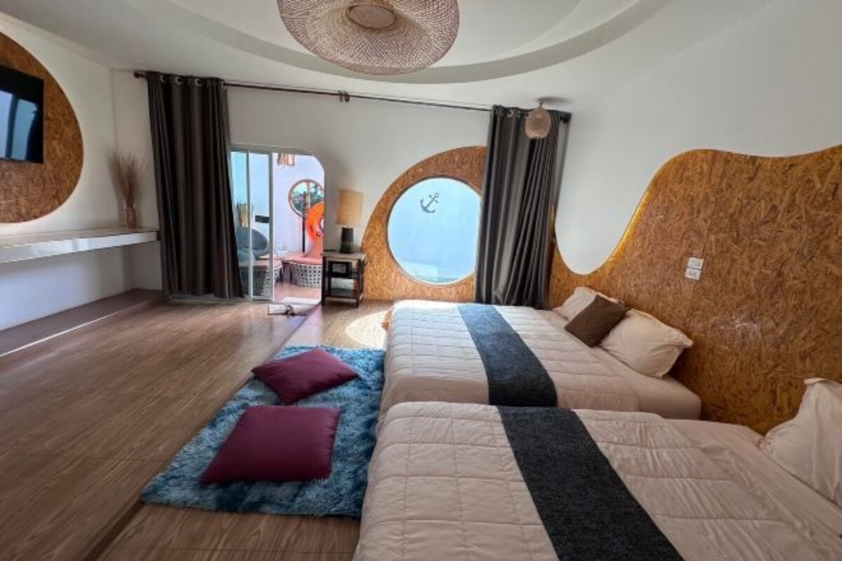 Un dormitorio moderno con dos camas, un ventanal grande y una pared de madera decorativa.