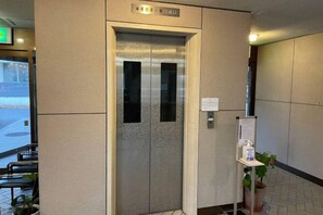 An elevator with a metallic finish, a sign above it, and a potted plant beside it. - Few Days Condominium Jozankei Room 302 (Sapporo)