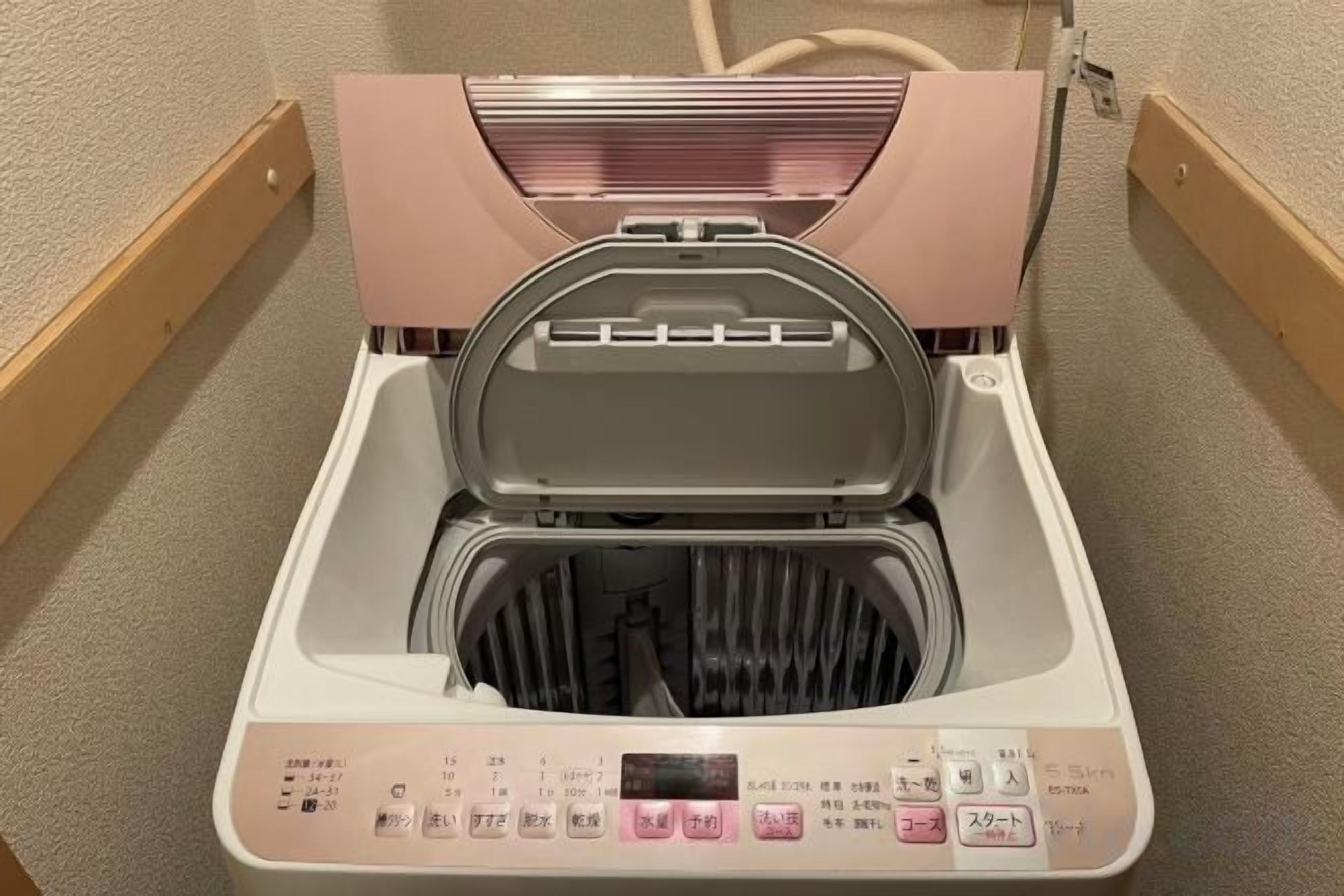 A compact, modern washing machine with a digital display and control panel, situated in a small, enclosed space.