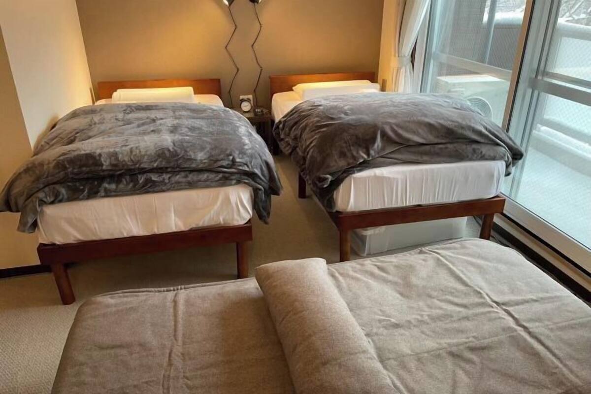 Habitació d'hotel amb dos llits, una finestra i un rellotge penjat a la paret.