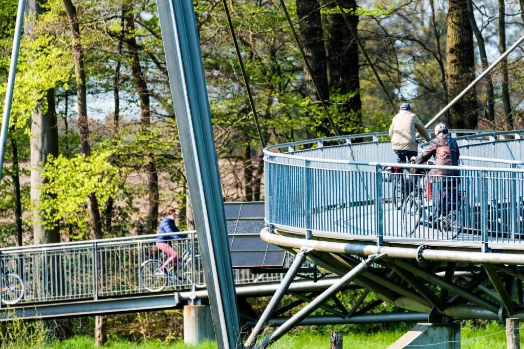 A pedestrian bridge with metal railings and a circular viewing platform.