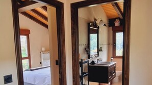 Un pasillo que lleva a un dormitorio con cama y un baño con lavamanos y espejo.