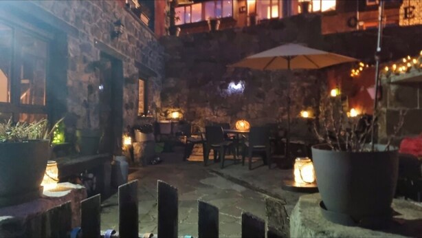 Un patio al aire libre con muros de piedra, mesas, sillas y plantas en macetas.