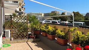 A rooftop terrace with potted plants and a view of parked cars and buildings. - Casa Mariuccia Cozy apartment near the waterfront Valencia (Alghero)