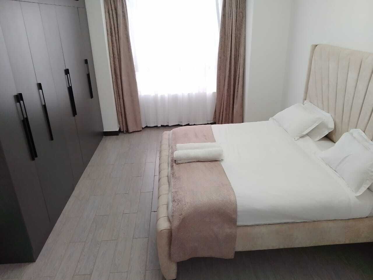 A bedroom with a bed, a wardrobe, and a window with curtains.