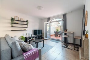 A modern living room with a sofa, coffee table, TV, and shelves with plants. - The Sun Terrace (Vigo)