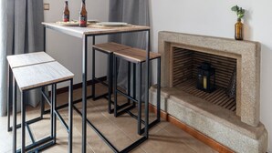 Ett litet, modernt rum med en öppen spis, en rund spegel och ett bord med två pallar.