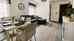 Een moderne woonkamer met een eethoek, een bank, een klok en een hanglamp.