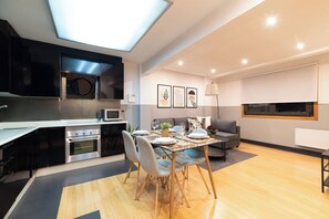 A modern kitchen with a dining area, featuring a built-in oven, microwave, and black cabinets. - Elegant Duplex Penthouse with Parking (Vigo)