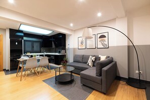 A modern living room with a grey sofa, a round coffee table, and a dining area with a glass table and chairs. - Elegant Duplex Penthouse with Parking (Vigo)