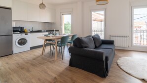 A modern kitchen with a dining area, a washing machine, and a sofa. - Balcony (Vigo)