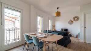 A modern living room with a dining area, large windows, a sofa, and a TV. - Balcony (Vigo)