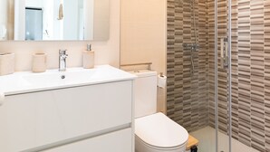 A modern bathroom with a glass shower enclosure, a white sink with a mirror, and a toilet. - Balcony (Vigo)