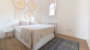 A bedroom with a bed, bedside table, wall art, and a window. - Balcony (Vigo)