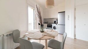 A modern kitchen with white cabinets, a washing machine, and a refrigerator.