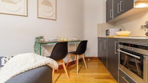 Une cuisine compacte dotée d’appareils électroménagers modernes, un coin repas avec deux chaises et un canapé.
