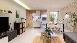 Un salon moderne avec un téléviseur, des meubles noirs, une table basse en bois et un coin repas comprenant des chaises et une table.