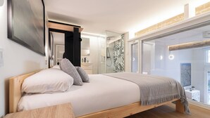 Un dormitorio moderno con una cama de madera, cabina de ducha de vidrio y vistas al exterior.