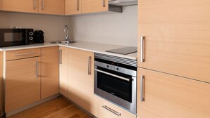 A modern kitchen with wooden cabinets, stainless steel appliances, and a wooden floor. - La Galeria de Principe (Vigo)