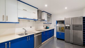 A modern kitchen with blue cabinets, stainless steel appliances, and a dishwasher. - House Vigo (Vigo)