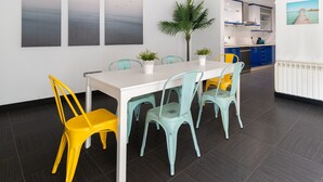 A dining area with a white table, teal and yellow chairs, and a potted plant. - House Vigo (Vigo)