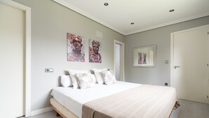 A bedroom with a bed, white walls, and artwork on the wall. - House Vigo (Vigo)