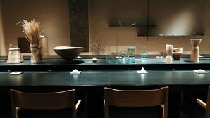 Un restaurant doté d’un long comptoir, de chaises en bois et de divers objets de décoration et de verrerie.