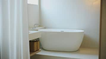 Ein modernes Badezimmer mit einer freistehenden Badewanne, einem Waschbecken und einem Spiegel.