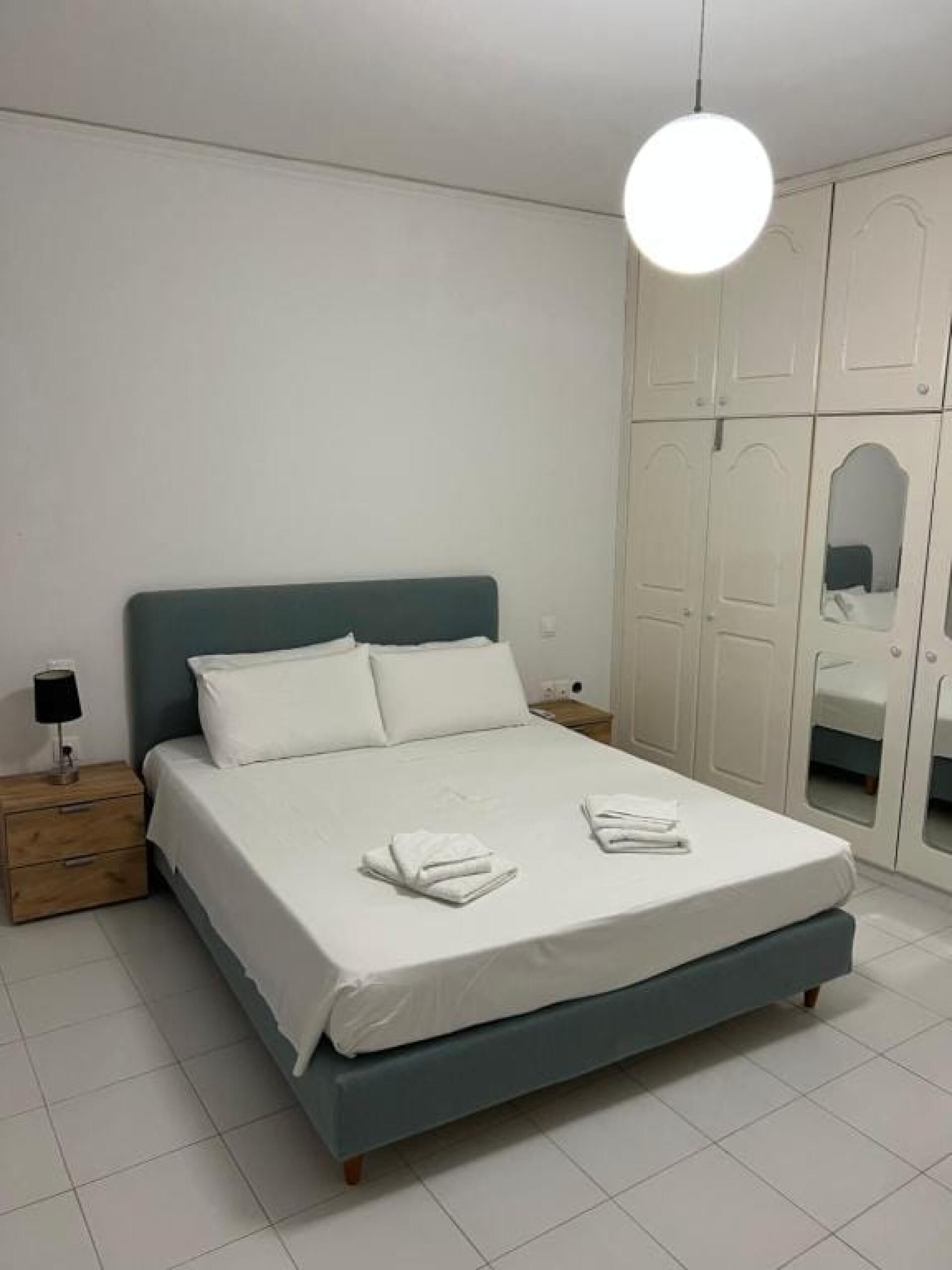 Une chambre à coucher avec un lit, une table de chevet, une lampe et une armoire.