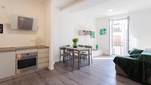 Una cocina moderna con horno y microondas integrados, un comedor con mesa y sillas, y un balcón con vistas.