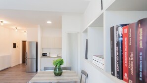 Una cocina moderna con refrigerador, microondas y comedor con mesa y sillas de madera.