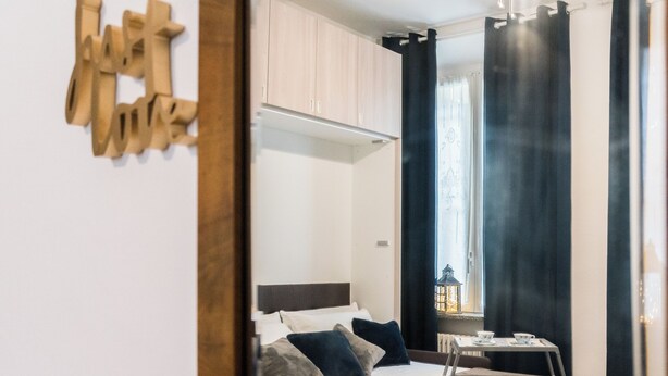 Un dormitorio con cama, mesita de noche, ventana con cortinas y vista a la ciudad.