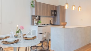 A modern kitchen with wooden cabinets, a built-in microwave, and pendant lights. - Como Liberty Suites - Garbo by Rent all Como (Como)