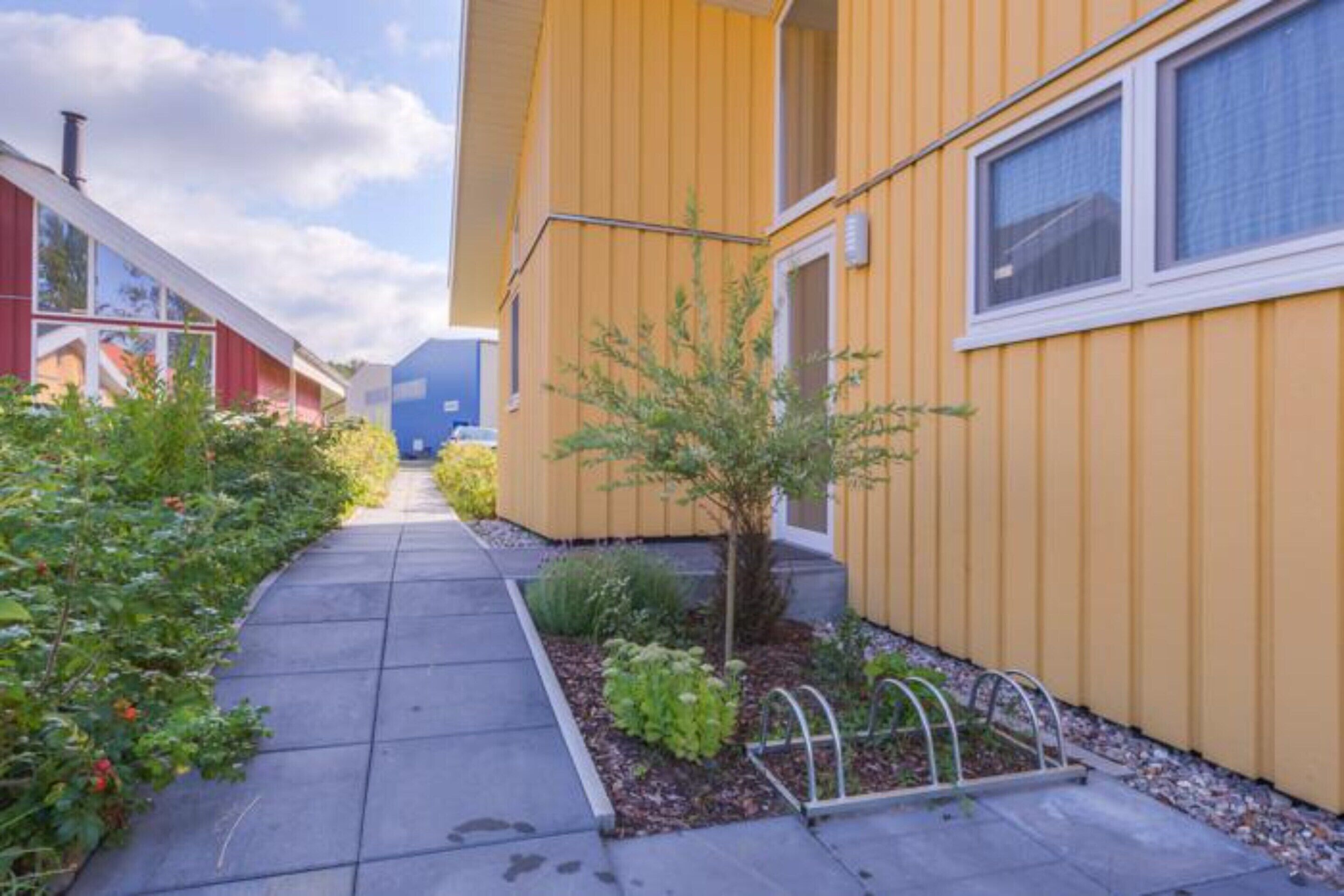 A yellow building with a narrow pathway and small trees.