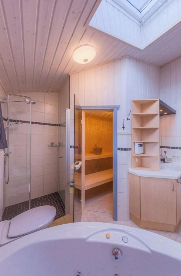 A modern bathroom with a glass-enclosed shower, a white bathtub, and wooden shelving. - Exklusives Skandinavisches Ferienhaus (Rechlin)