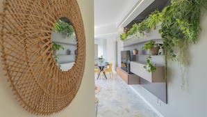 A modern interior with a woven wall art piece, a dining area with yellow chairs, and shelves with greenery. - Como Panorama by Rent all Como (Como)