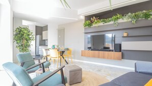 A modern living room with a sofa, chairs, a dining area, and a kitchen in the background. - Como Panorama by Rent all Como (Como)