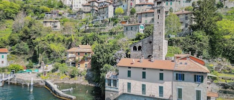 A coastal village with stone buildings, a prominent tower, and a clear view of the sea.