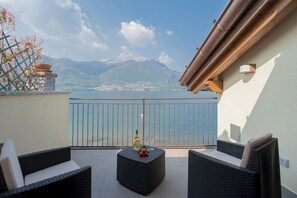 Ein Balkon mit Rattanmöbeln, einer Weinflasche und einem Weinglas auf einem Tisch.
