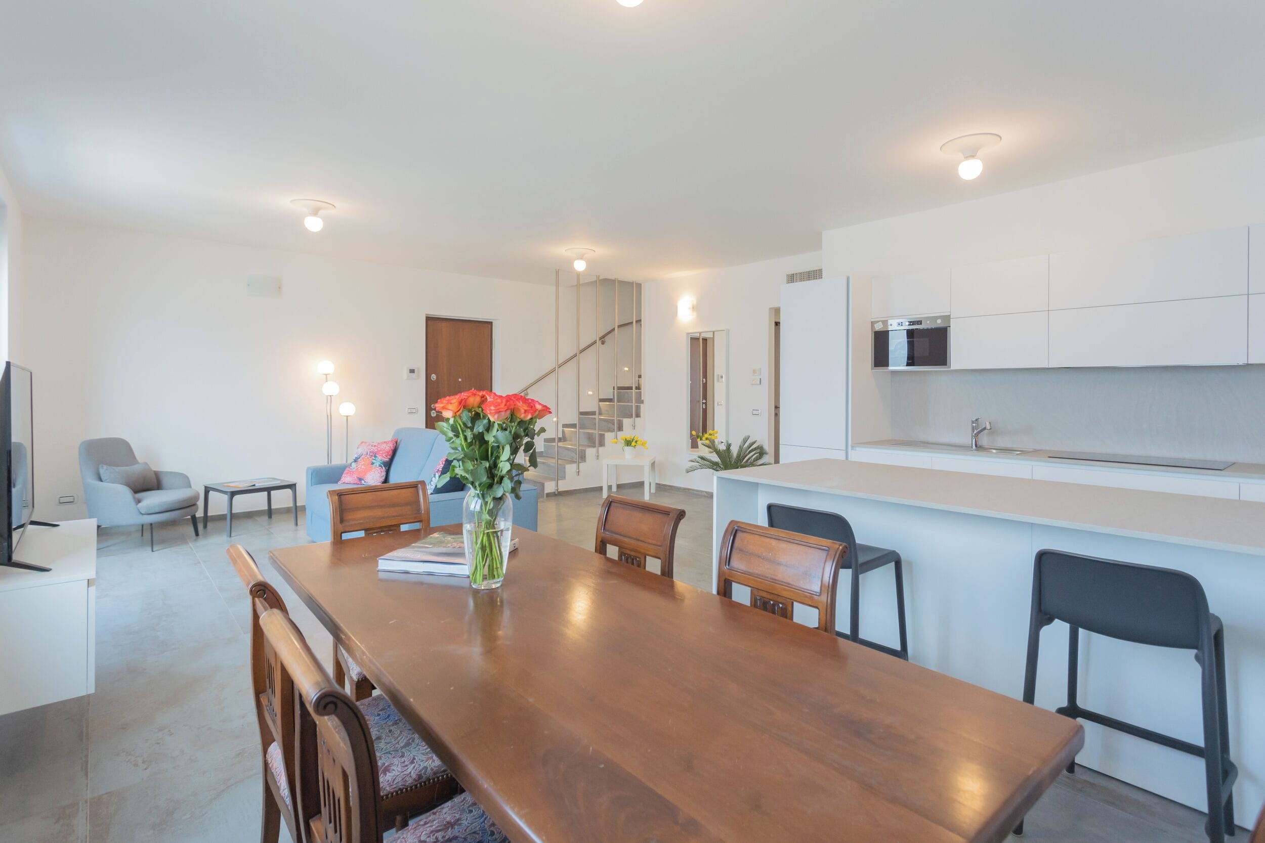 A modern kitchen with white cabinets, a built-in microwave, and a stainless steel sink.