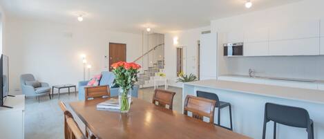A modern kitchen with white cabinets, a built-in microwave, and a stainless steel sink.