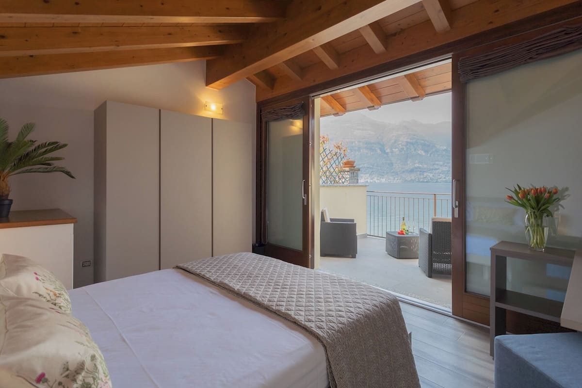 A bedroom with a bed, a wardrobe, and a balcony with outdoor furniture.
