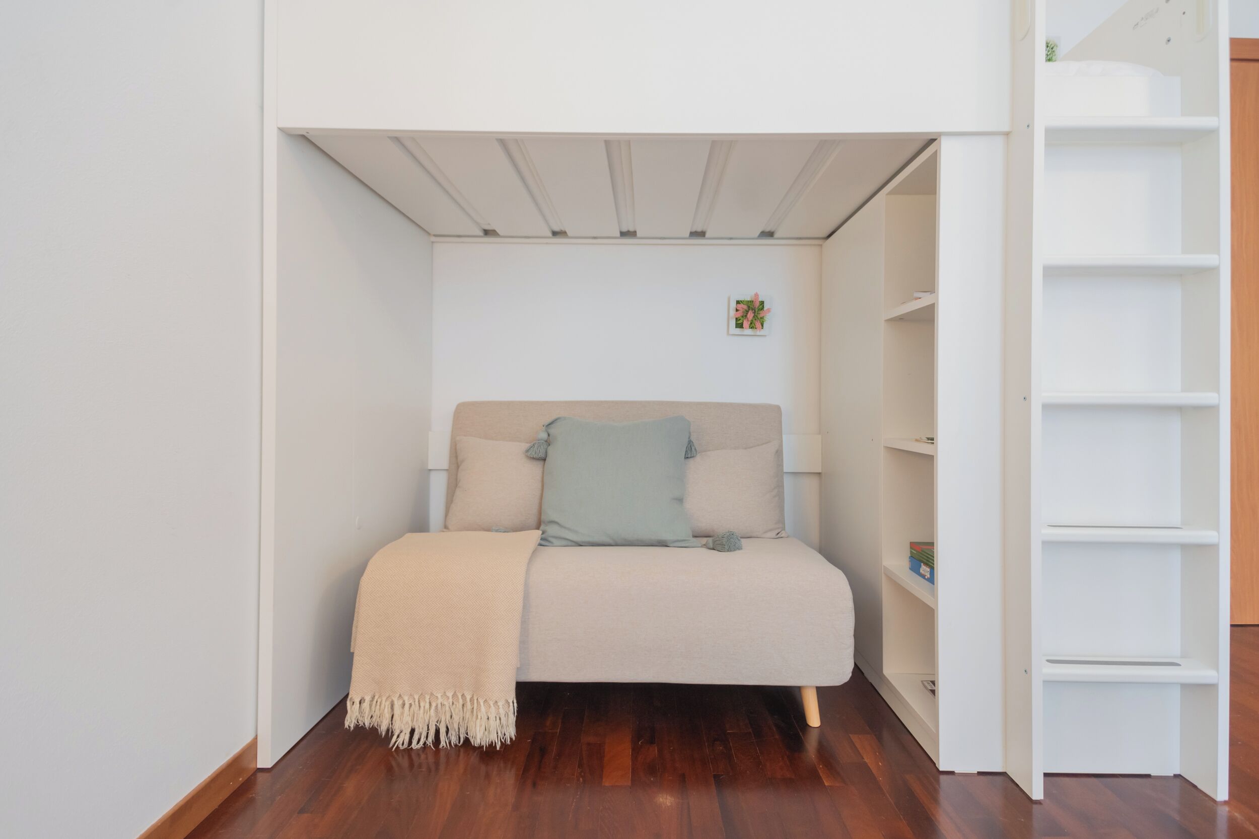 Ein kleiner, gemütlicher Raum mit einem Bett, einer Regalwand und einem kleinen dekorativen Gegenstand an der Wand.