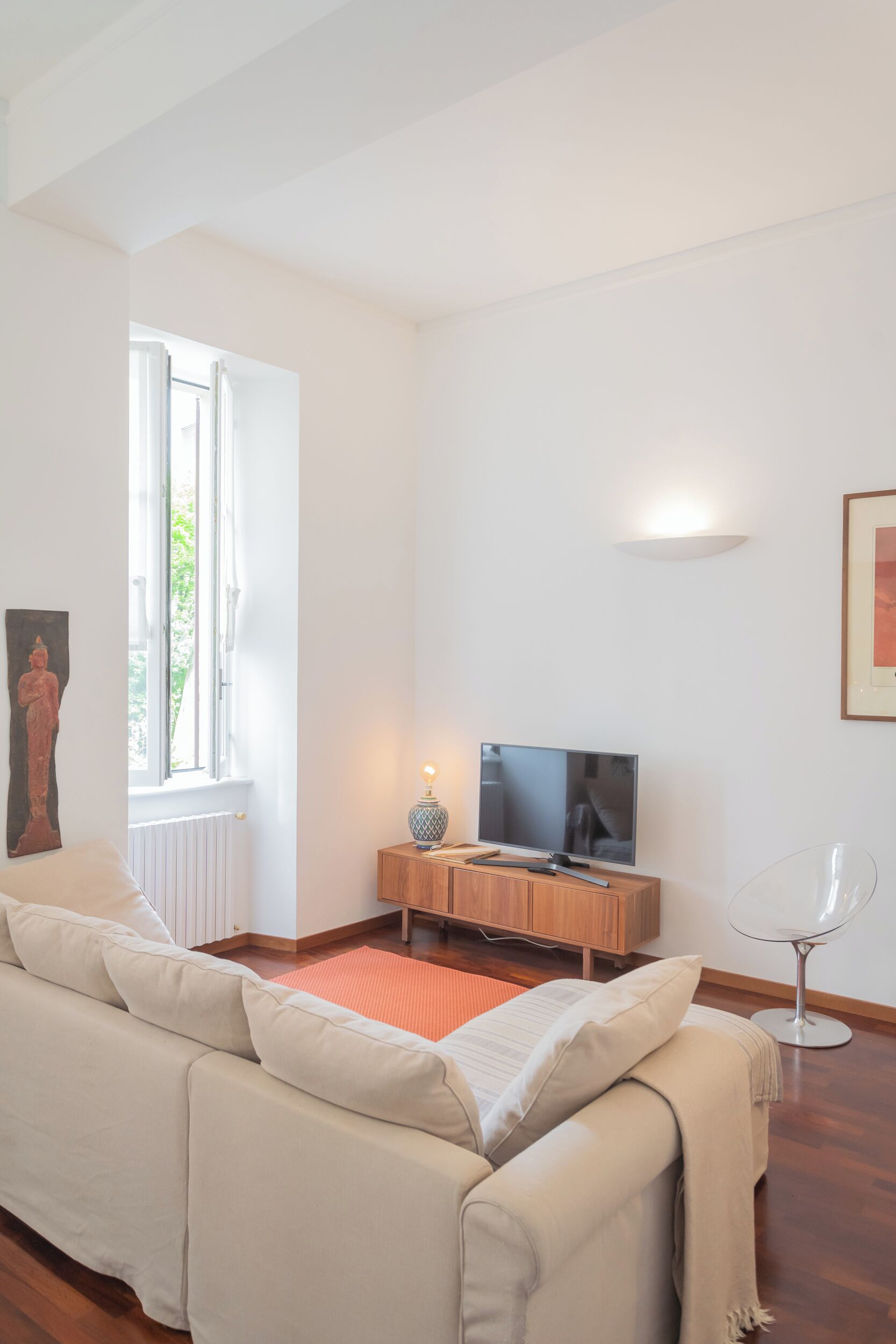 A living room with a sofa, a TV, a wooden cabinet, and a lamp.