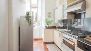A modern kitchen with white cabinets, a black stove, and a clock on the wall. - Filanda - Best Lakefront in Como by Rent all Como (Como)