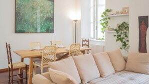 A dining area with a wooden table and chairs, a sofa, and a large abstract painting on the wall. - Filanda - Best Lakefront in Como by Rent all Como (Como)